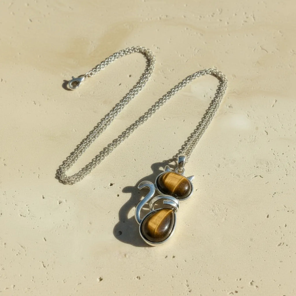 Collier pendentif chat en oeil de tigre avec chaîne complète sur fond travertin beige