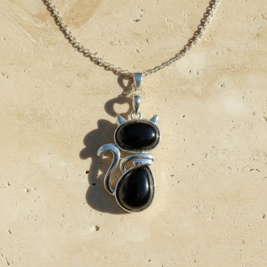 Pendentif chat en pierre naturelle agate noire sur fond travertin beige
