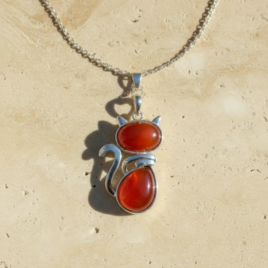 Pendentif chat en pierre naturelle agate rouge sur fond travertin beige