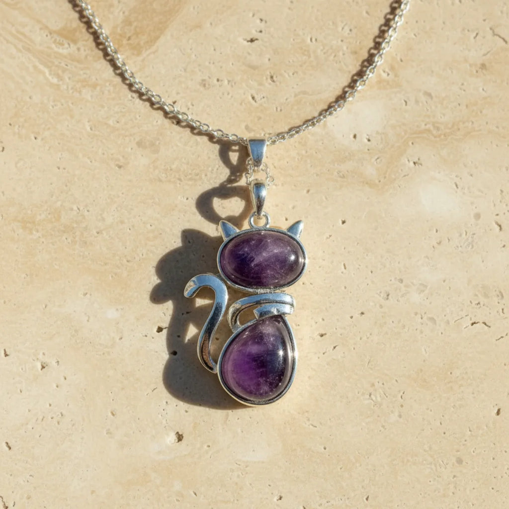 Pendentif chat en pierre naturelle améthyste sur fond travertin beige