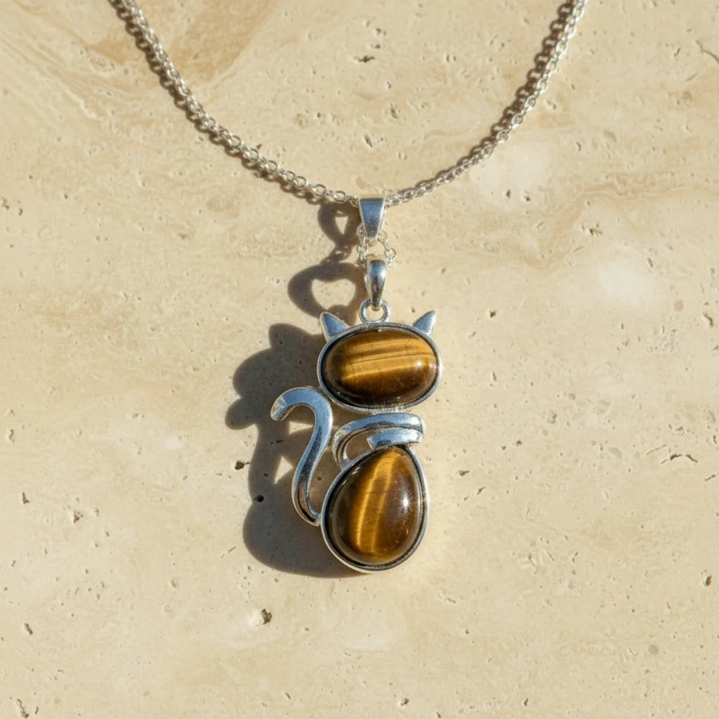 Pendentif chat en pierre naturelle oeil de tigre sur fond travertin beige