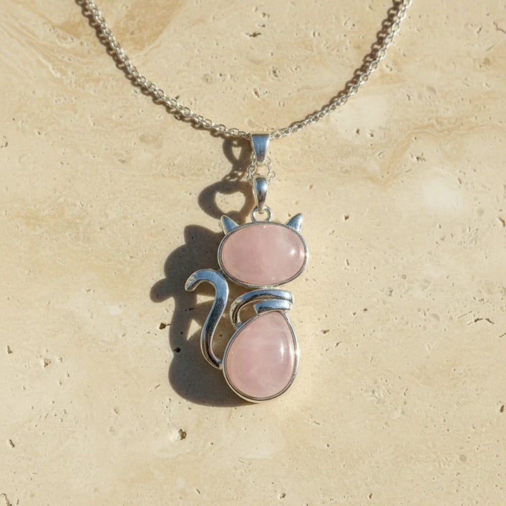 Pendentif chat en pierre naturelle quartz rose sur fond travertin beige